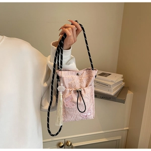 Detail of pink embroidered butterfly pattern and white tassel on the jacquard bucket bag