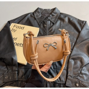 Detail of silver bow hardware and knotted strap on apricot crescent shoulder bag