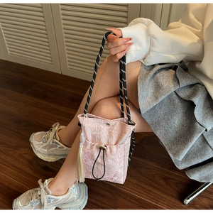 Detailed view of pink lace drawstring bucket bag with butterfly embroidery and tassel