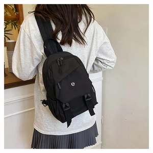 Détail d'un sac à dos en nylon noir avec étiquettes de mode porté par un mannequin