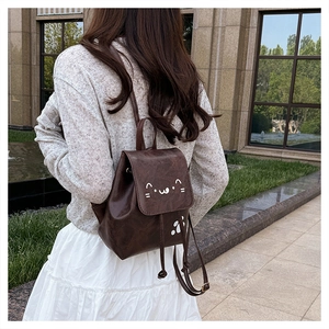 Close-up of brown PU leather backpack featuring cute white cartoon cat face and paw print
