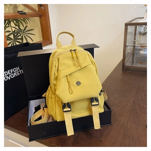 Détail d'un sac à dos jaune avec cordon de serrage et boucles noires en nylon imperméable