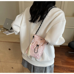 Detail of pink butterfly embroidery on a pleated drawstring bucket bag with long tassel
