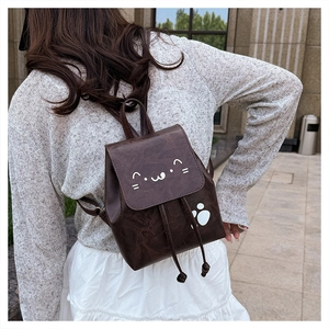 Detail of dark brown mini backpack featuring a white cat face print on vintage synthetic leather