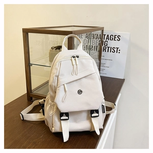 Détail de la texture d'un sac à dos en toile blanc cassé sur une table en bois