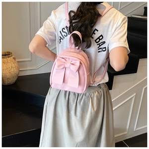 Detail of pink mini backpack featuring a large decorative bow and premium PU leather finish