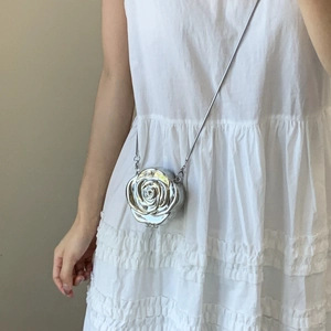 Pochette argentée en forme de rose avec bandoulière sur une robe blanche élégante
