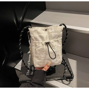 Detailed embroidery of white butterflies and floral lace on a pleated bucket bag