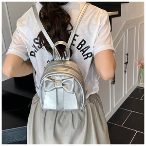 Close-up of a silver metallic mini backpack featuring a stylish oversized bow decoration