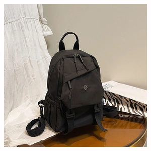 Détail du sac à dos noir avec plusieurs poches de rangement et logo métallique discret