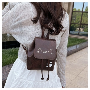 Close-up of a dark brown PU leather mini backpack with a cute white cat face and paw print