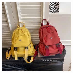 Détail de mini sacs à dos en nylon colorés sur un banc avec bretelles réglables et poches