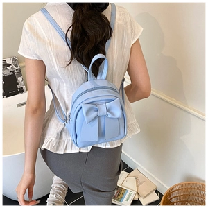 Close-up of a light blue mini backpack with a large bow detail on a fashion model