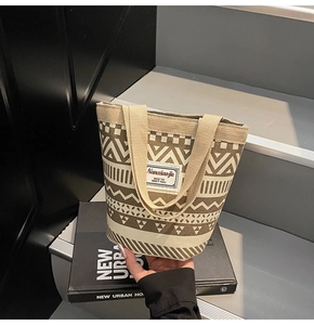 Close-up of ethnic geometric pattern canvas bucket bag placed on fashion books