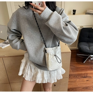 Detailed shot of white lace drawstring bucket bag with fringe trim on female model