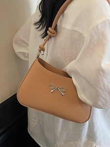 Minimalist light brown leather shoulder bag with silver bow hardware and knot strap details