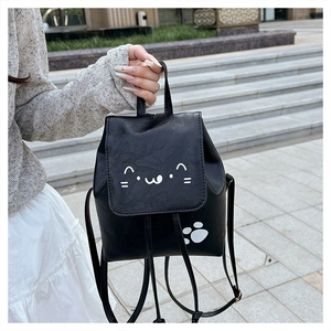 Detail of a mini black PU leather backpack with a cute white cartoon cat face and paw