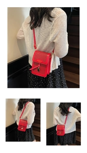 Detail of red quilted crossbody phone bag showing woven texture and gold brand logo