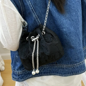 Floral jacquard bucket bag with silver chain and pearl drawstring on denim outfit