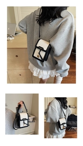 Detail view of woven black and white crossbody phone bag with metal circular ornament