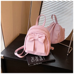 Detail of pink mini backpack with ribbon bow showing adjustable straps in the mirror