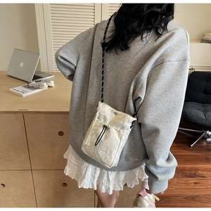 Detail of a white bucket bag with butterfly embroidery and tassel on a female model