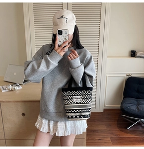 Close-up of geometric pattern canvas bucket bag with logo patch in a casual outfit