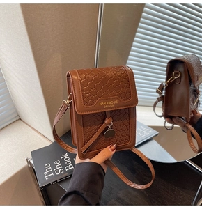 Detail of a brown woven leather crossbody phone bag with gold branding and metal charm