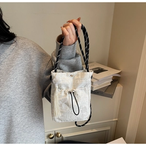 Detail of white lace bucket bag featuring butterfly embroidery and fringe tassel charm