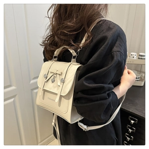 Détail d'un sac à dos en cuir PU crème avec nœud et breloque cœur porté par le mannequin