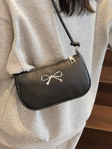 Minimalist black crescent shoulder bag with silver metallic bow detail and leather texture