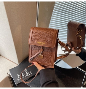 Detail of brown embossed PU leather phone bag with gold lettering and slim shoulder strap