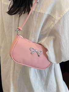 Pink crescent shoulder bag with silver metal bow accent and minimalist chic design