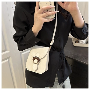 Détail d'un mini sac bandoulière blanc crème avec une boucle vintage en grain de bois foncé