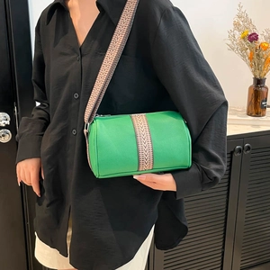 Green leather barrel bag with vintage geometric strap shown on model in modern setting