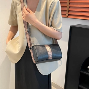 Classic black leather Boston bag with bohemian woven strap shown as a crossbody carry
