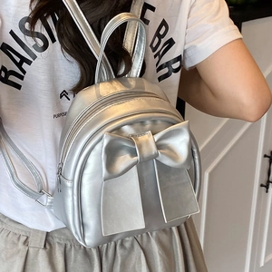 Silver bow backpack for women with metallic finish shown from a back-view angle