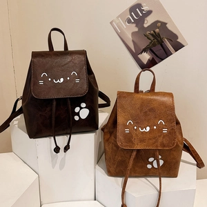 Mini PU leather bow backpacks with cat prints in brown and caramel shades on white pedestals