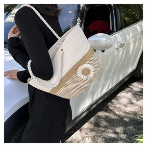 Outdoor shot of a woven color-block tote bag with a white daisy floral applique detail