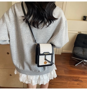 Black and white crocodile texture mini crossbody bag worn by a model in a home setting