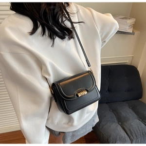 Detail of minimalist black PU leather crossbody bag featuring a golden twist-lock closure