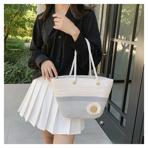 Detailed close-up of a woven tote bag with a white daisy ornament and grey stripes