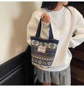 Close-up of ethnic canvas bucket bag featuring elephant prints and leather brand tag