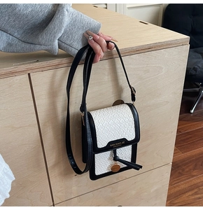Detail of hand-held mini crossbody bag with black trim and white woven leather texture