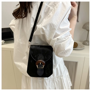 Détail du petit sac carré noir en velours avec boucle en bois rétro porté par le modèle