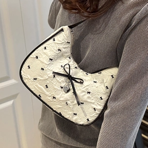 Sac sous le bras blanc texturé avec imprimé nœuds noirs et pendentif cœur sur modèle