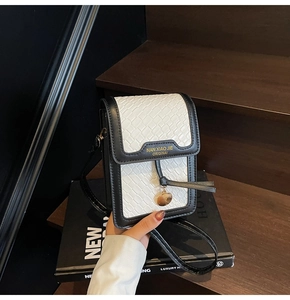 Close-up of black and white quilted crossbody phone bag with gold metal logo detail