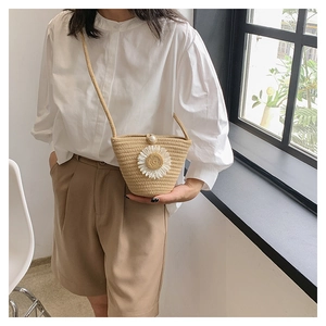 Détail du sac en paille tressée avec fleur de marguerite et fermeture à bouton perle