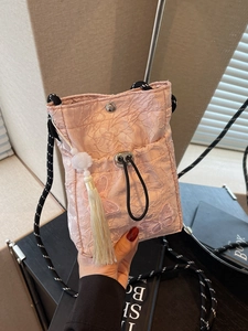 Pink lace bucket bag with butterfly embroidery and woven strap in a handheld view