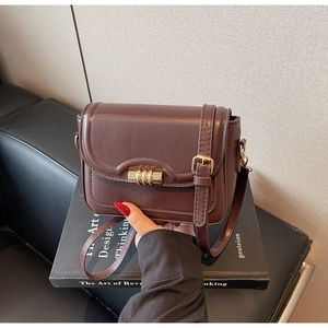 Detail of dark brown crossbody bag with matte faux leather and gold metal buckle